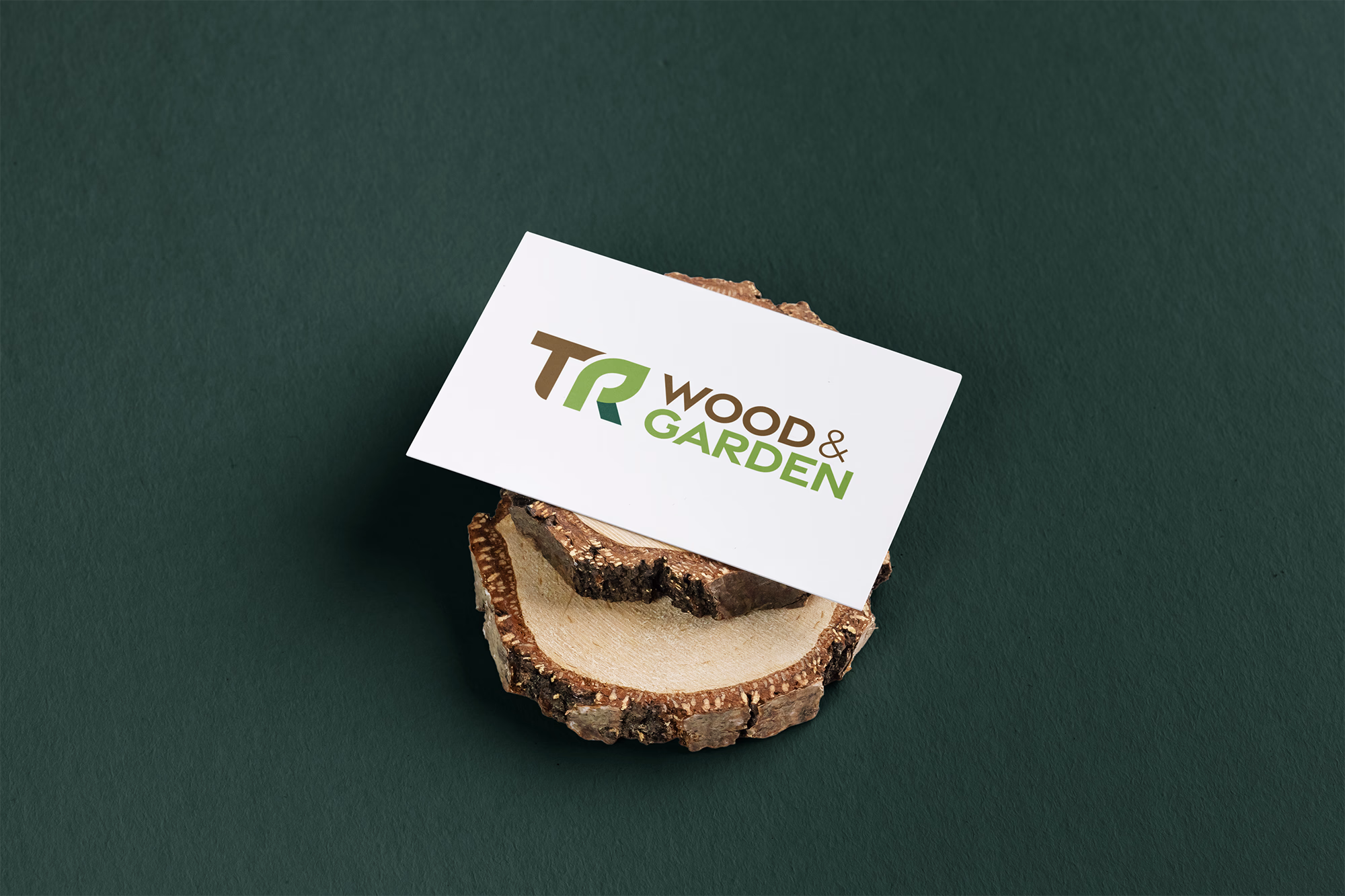 Visitenkarte mit "Wood & Garden"-Logo auf Holzscheibe vor grünem Hintergrund.